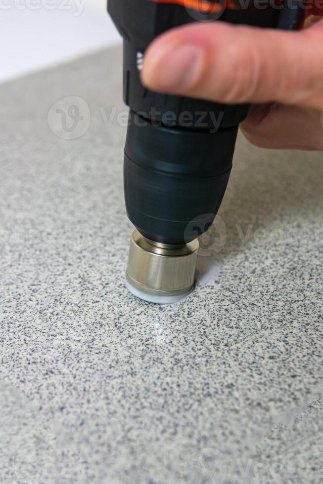 rotating diamond core drill bit starts drilling into a stone slab photo