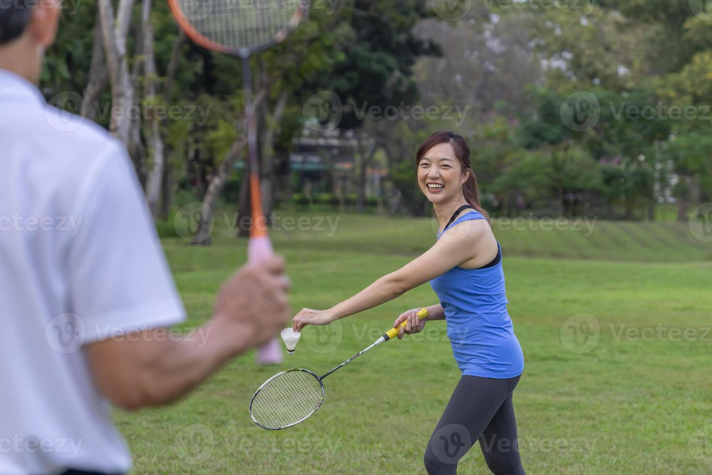 young attractive asian woman enjoy holiday time playing badminton with senior father outdoors in the park,family lifestyle sport recreation concept photo