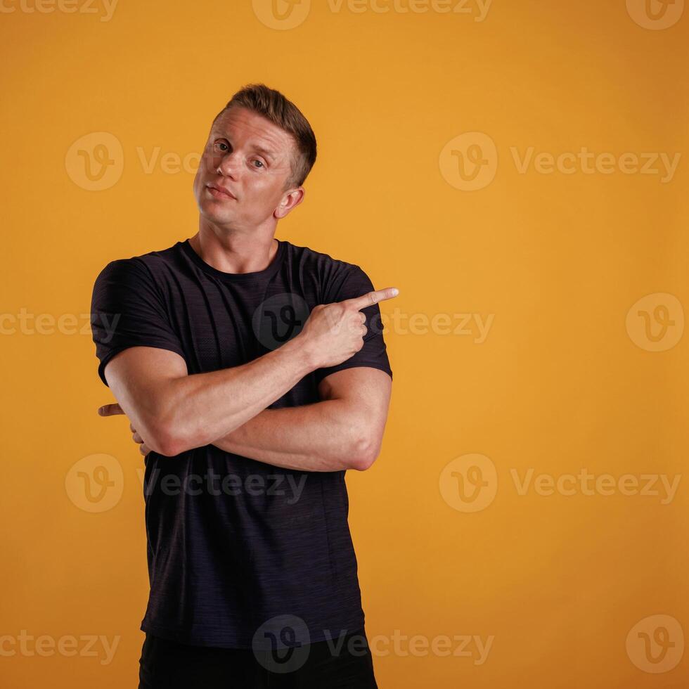 Showing to the side, pointing.,, Man ,is ,against background in the studio photo