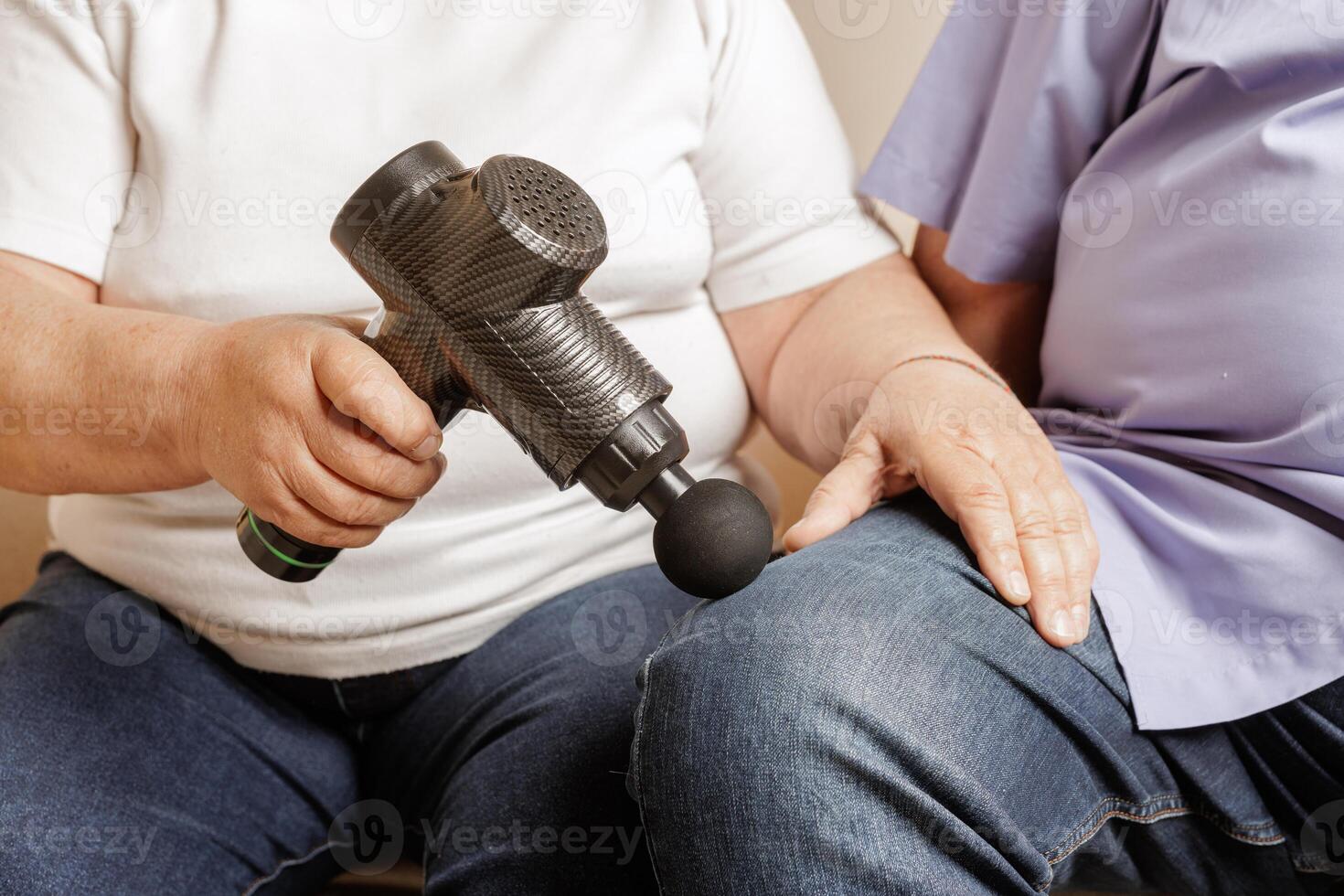 Elderly Using Percussion Massage Gun on Knee Pain Relief and Recovery with Electric Handheld Massager photo