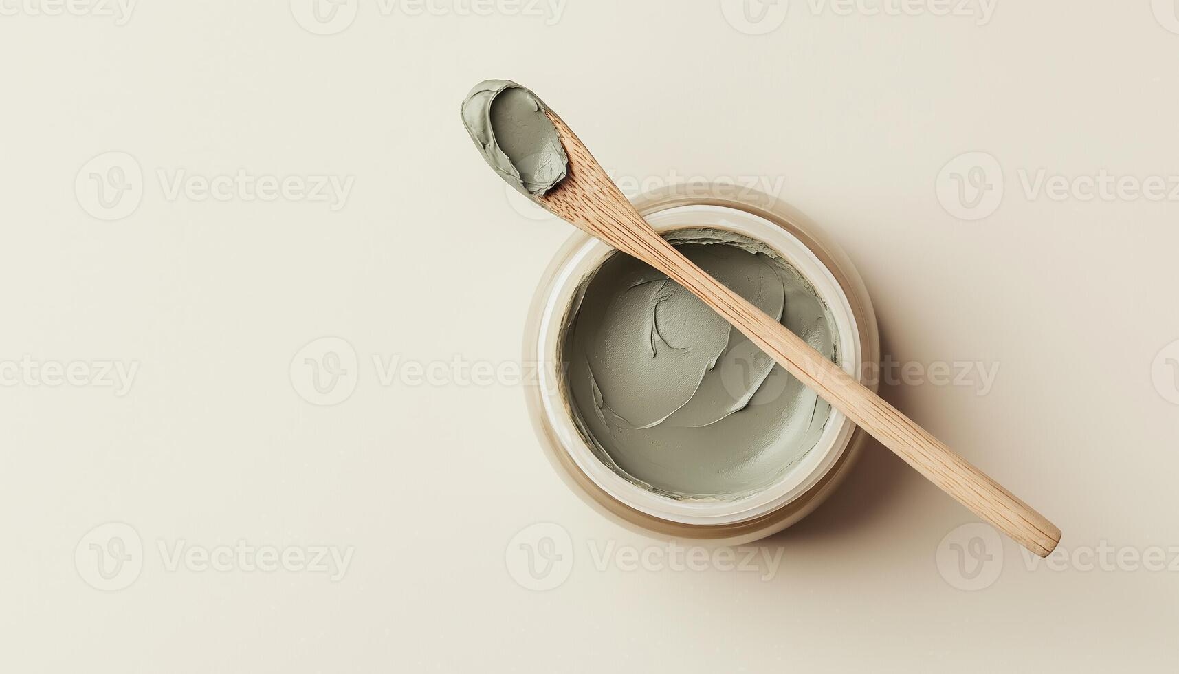 Clay mask on glass jar and spoon for skincare routine treatment on beaige background photo