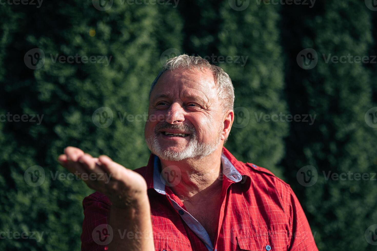oyful Senior Man in Red Shirt Enjoying a Sunny Day in the Garden photo