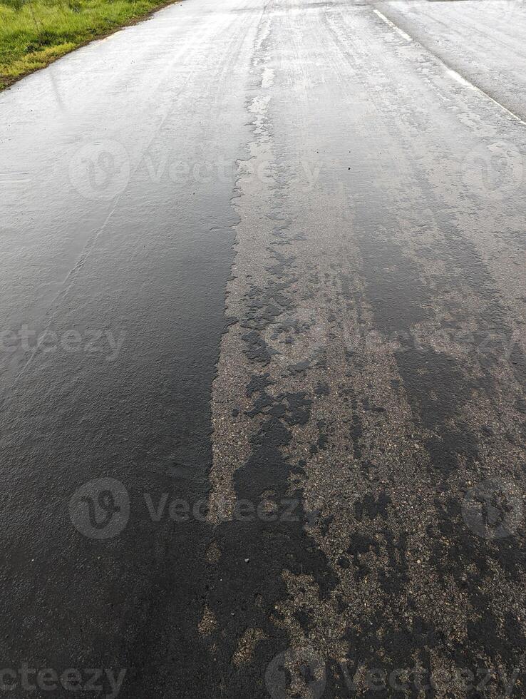 Failing road surface in Wales, showing deterioration, construction site, rain-wetted tarmac. photo