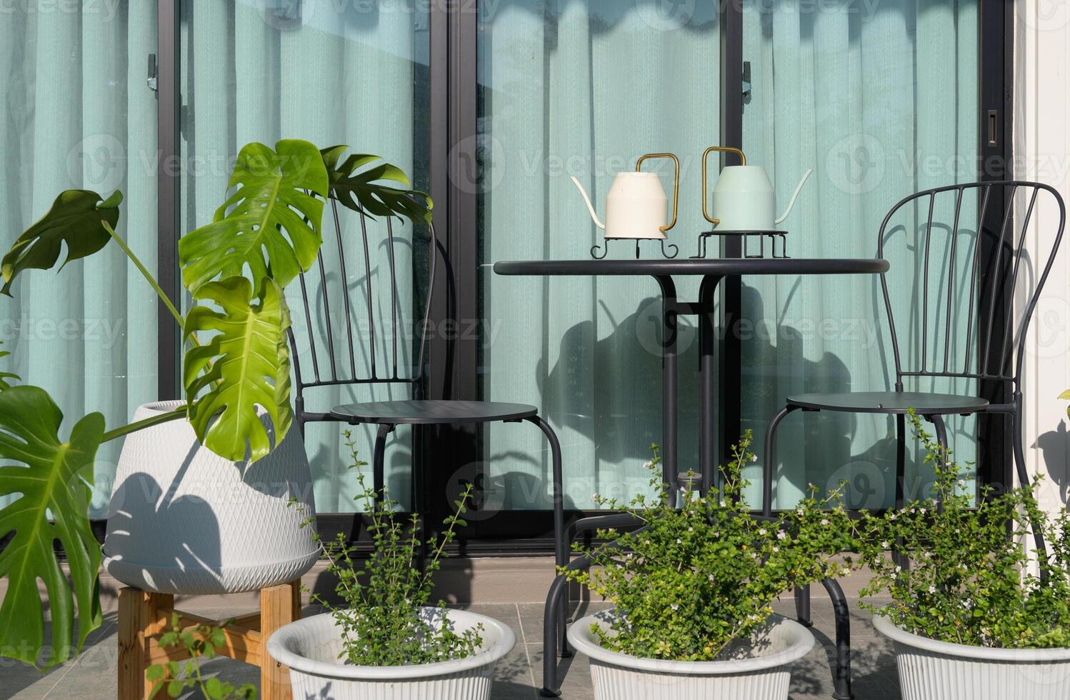 Metal table and chairs with green plants in flower pots near the window at home photo