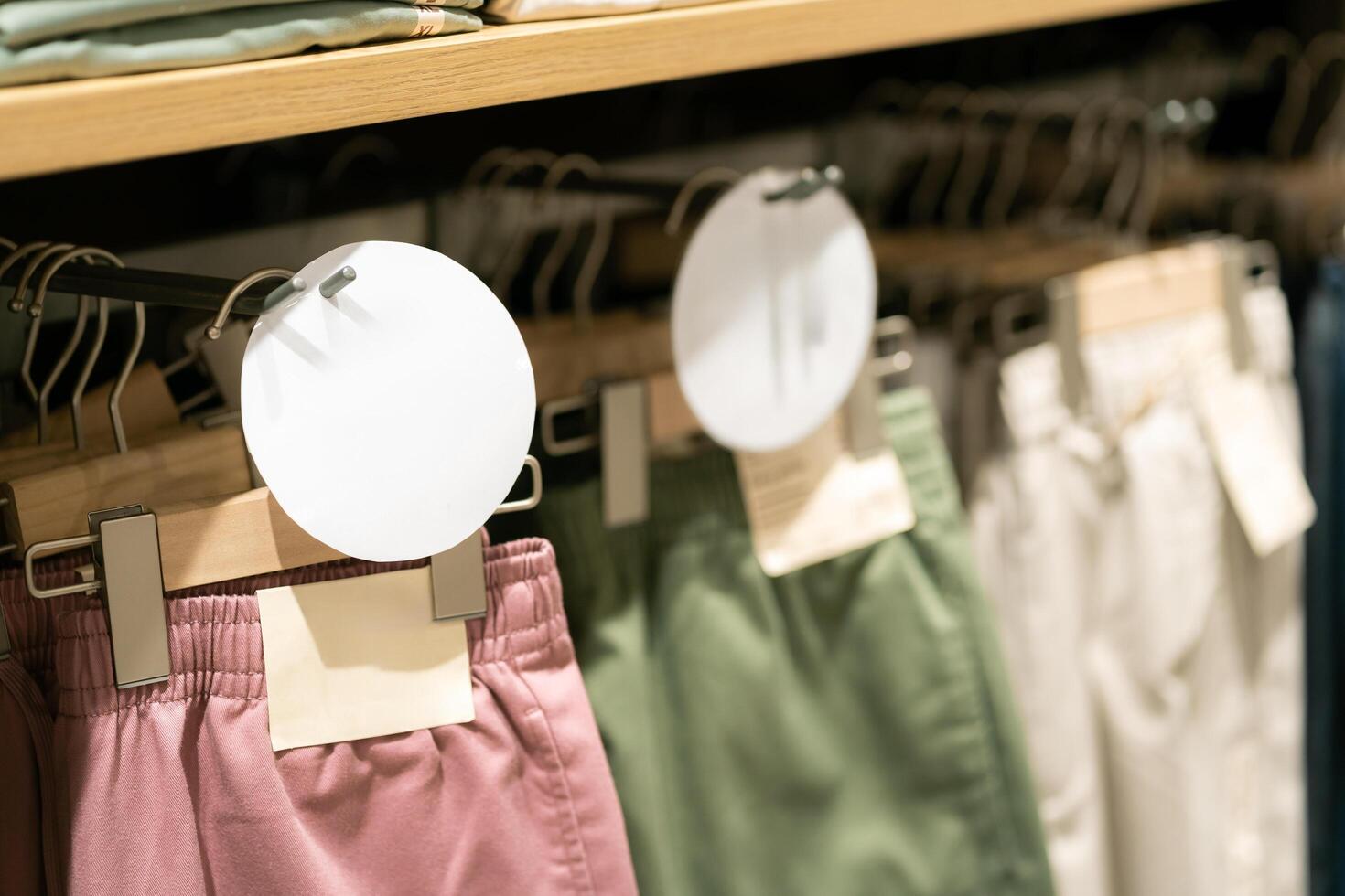 Fashion pants many colors hang on a shelf in a designer clothes store. Clothing hanging on a clothing rack in a store. photo