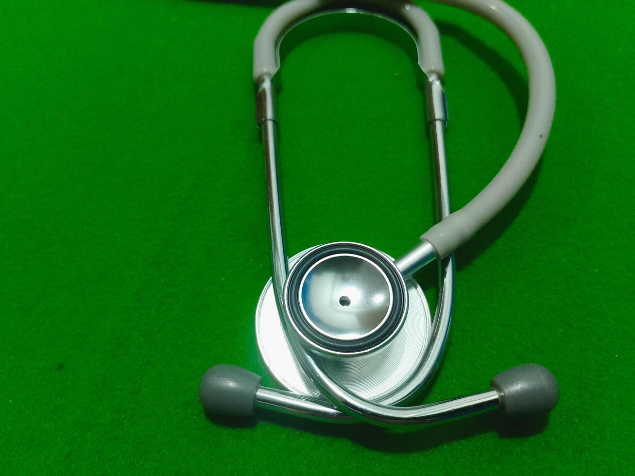 Medical stethoscope isolated on surgical green drape fabric background photo