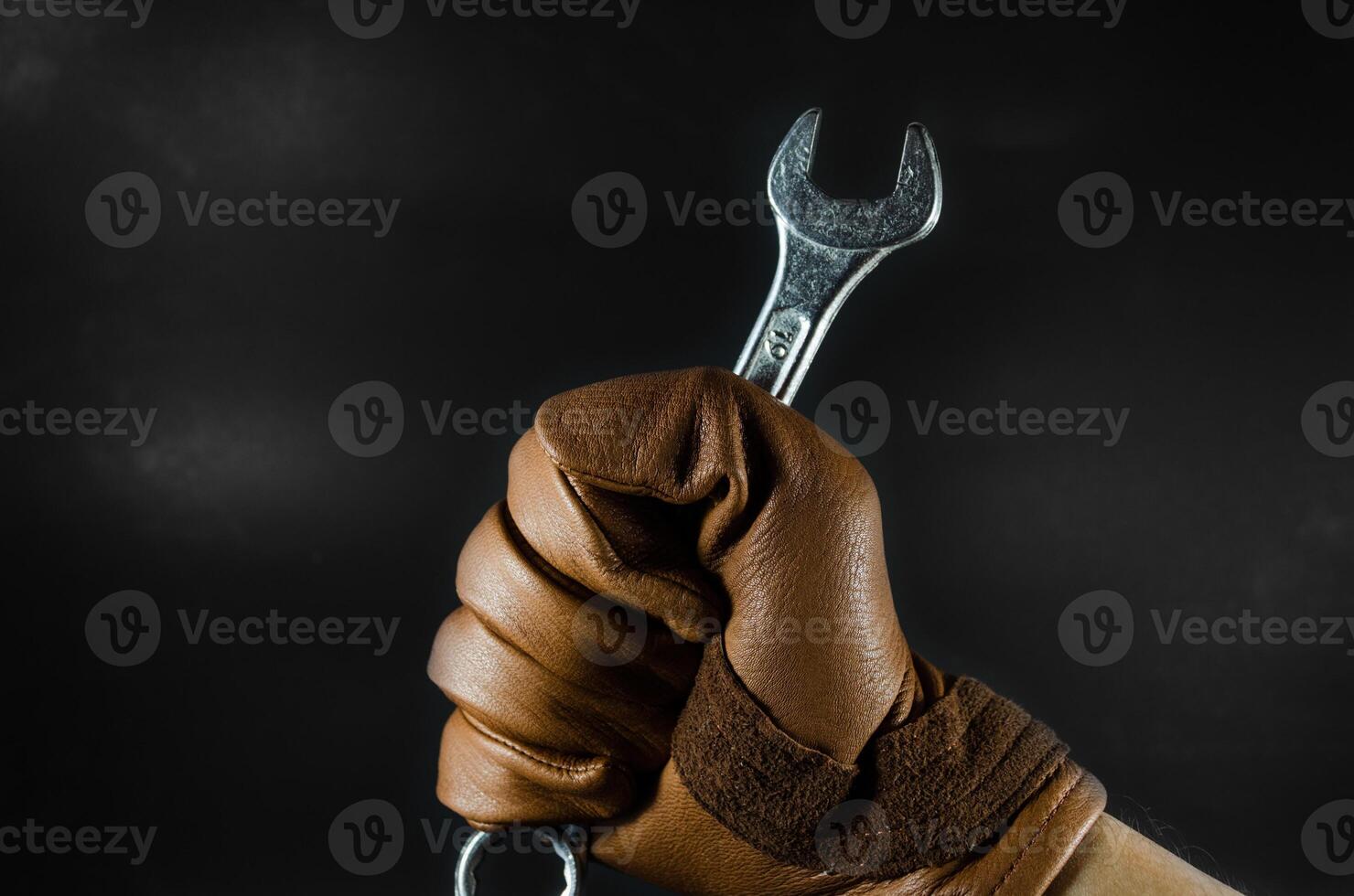 a wrench was holding by leather glove man hand in dark light photo