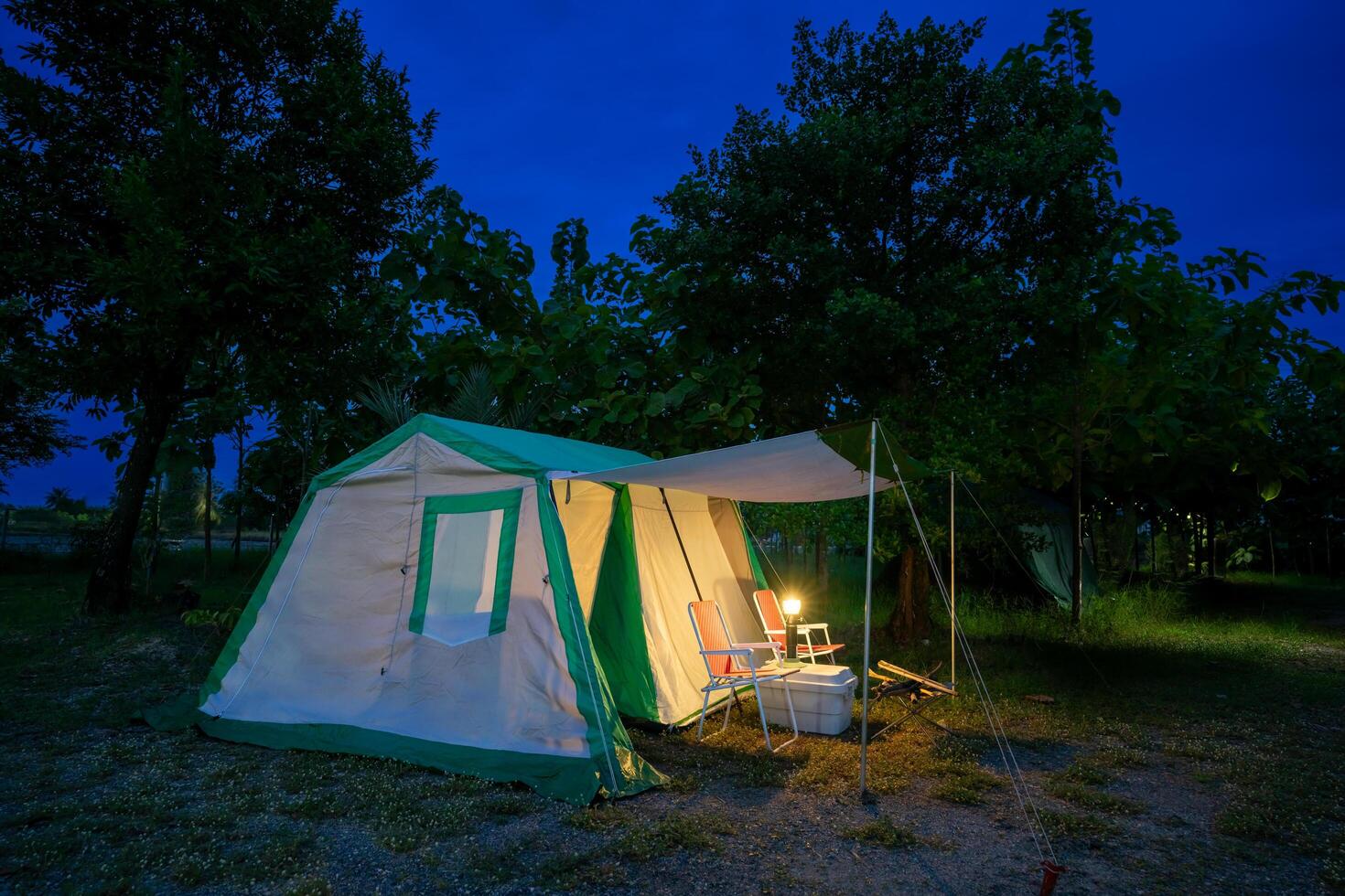 Camping tents at night, vintage cabin tents, antique oil lamps, retro chairs, and a group of camping tents with outdoor facilities photo