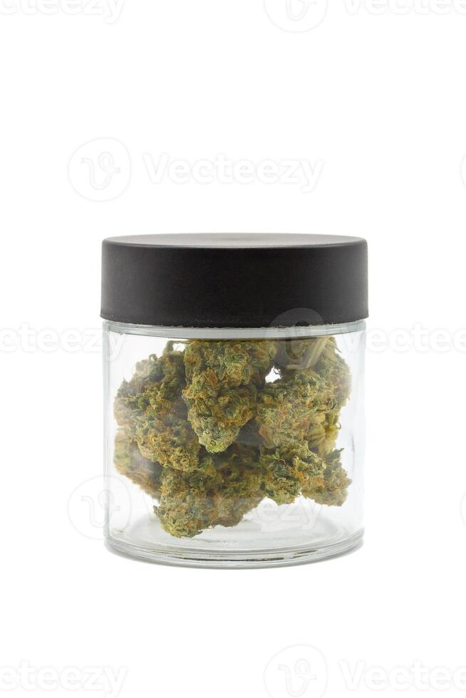 Cannabis flower buds in glass jar science on white isolated background. Dried marijuana buds in glass on white background. photo