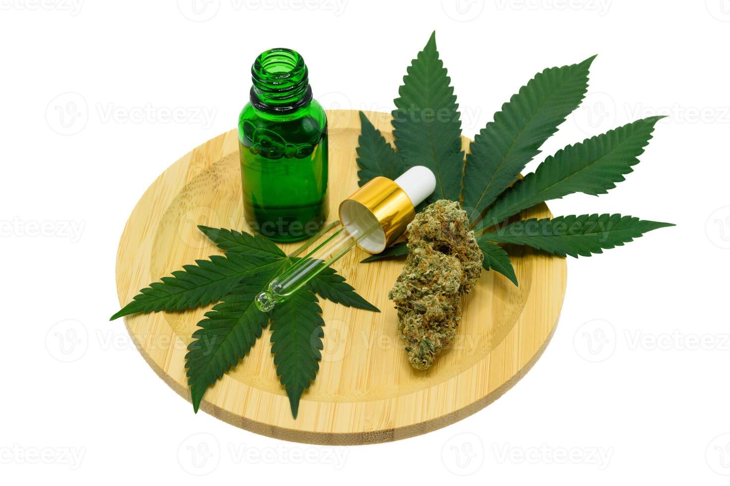 Cannabis flower buds with green dropper bottle and green leaf on a wooden plate on white isolated background, Scientists research CBD and THC extract oil from marijuana in pharmaceutical industry. photo