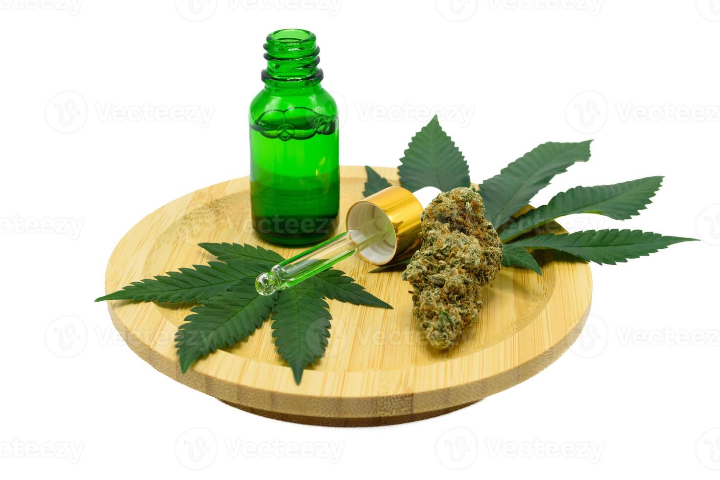 Cannabis flower buds with green dropper bottle and green leaf on a wooden plate on white isolated background, Scientists research CBD and THC extract oil from marijuana in pharmaceutical industry. photo