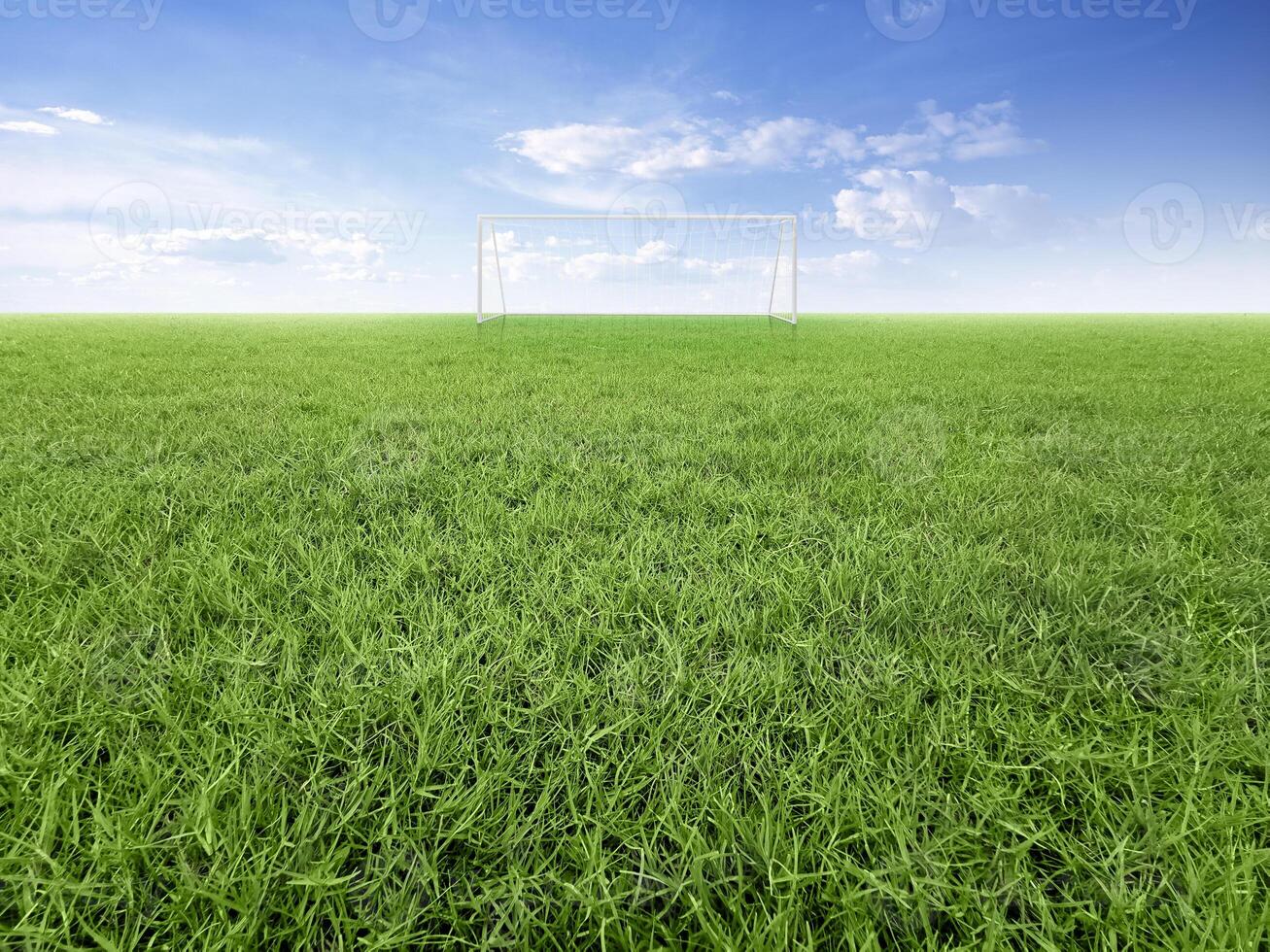 Empty football goal on green grass field with blue sky and white clouds photo