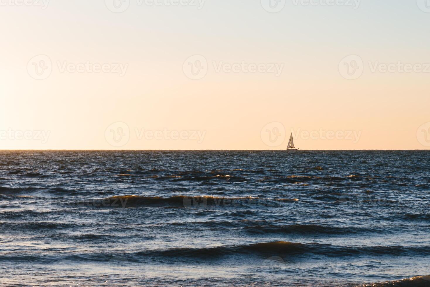 Sailing boat on the horizon during sunset photo