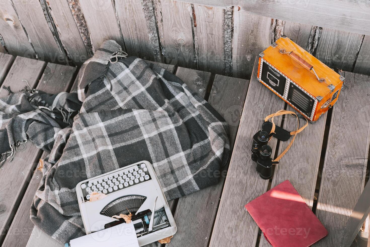 typewriter, blanket, radio and binoculars on a wooden floor. Workplace of a freelance writer against the background of a wooden house and floor photo