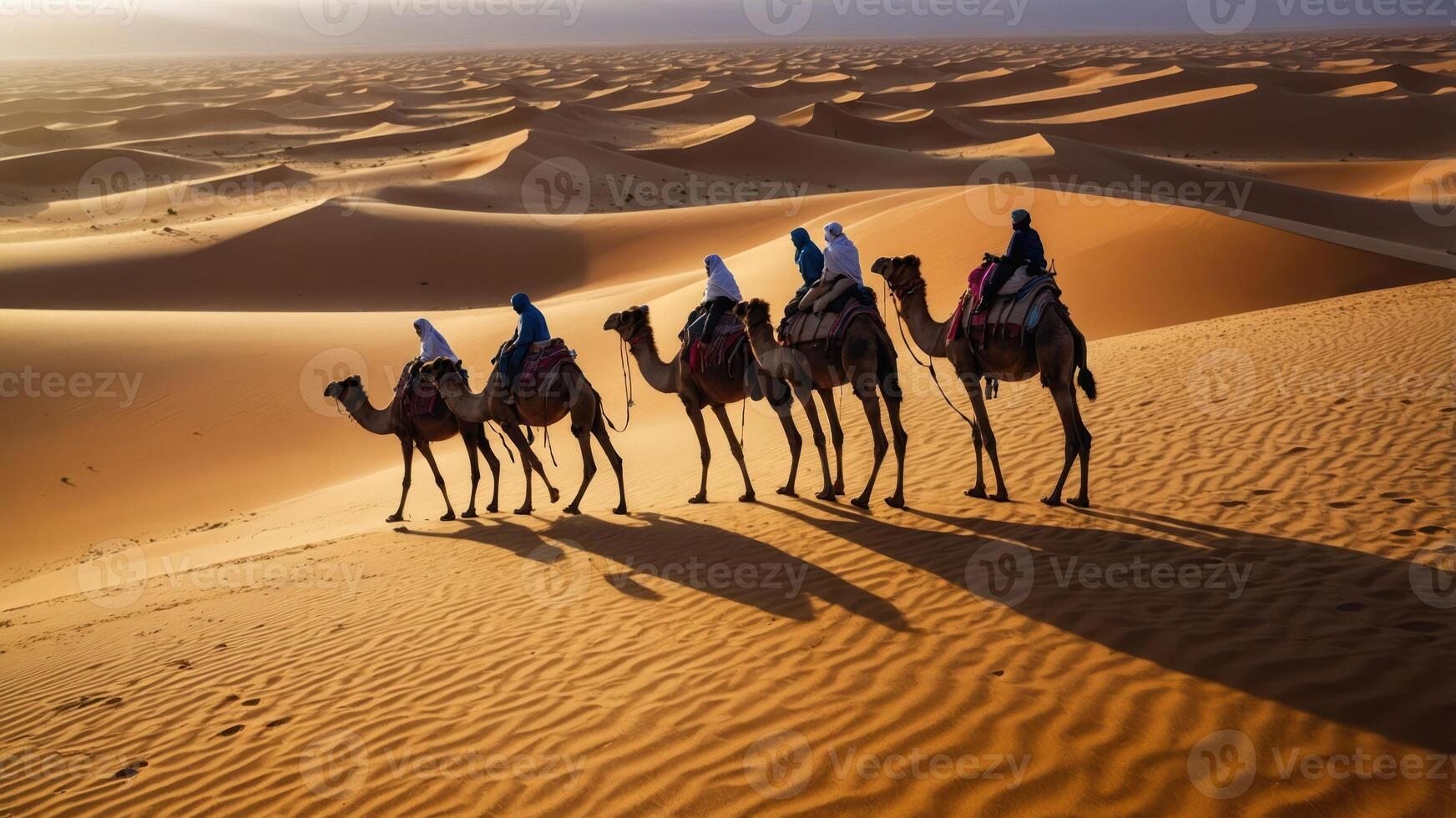 A caravan of camels traversing sand dunes under a golden sky. photo