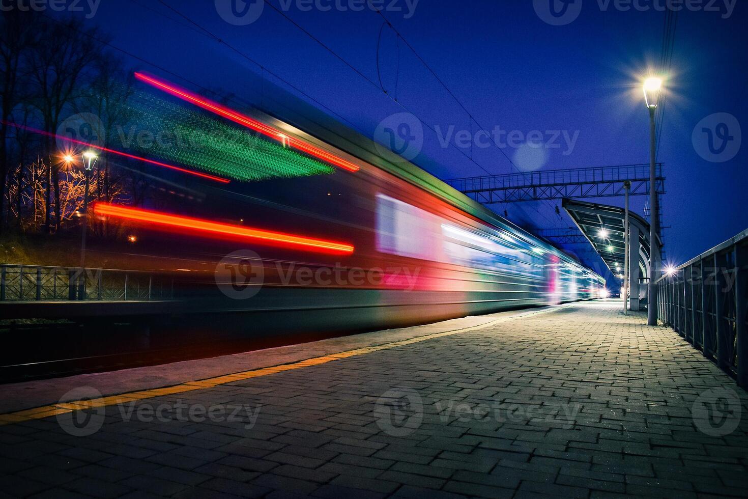 Evening arrival of the train on an empty platform. Photo taken with a shutter speed. Rays of light. Blur. Evening railway station.