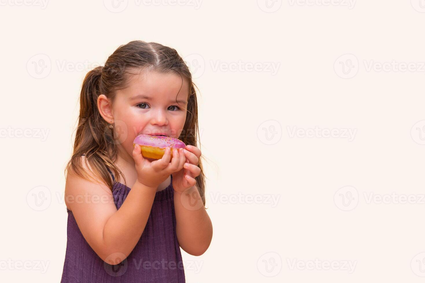 girl in a dress bites a delicious, sweet, pink donut photo