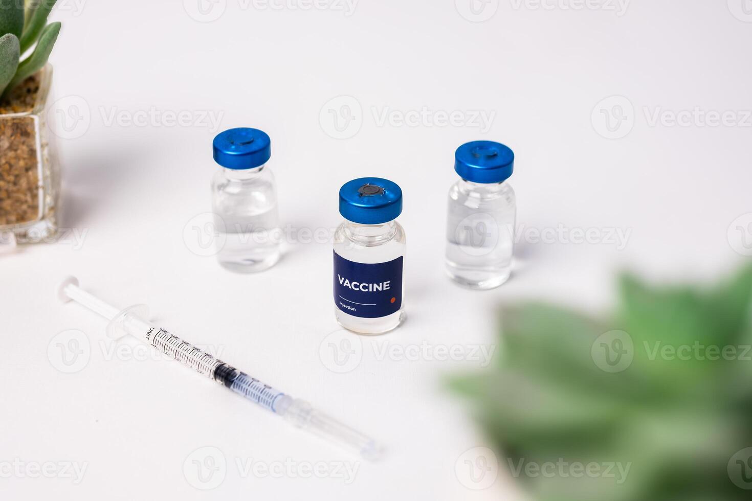 top view of some vaccines with ornamental plants on the table, inside the clinic room. health and medical concepts photo