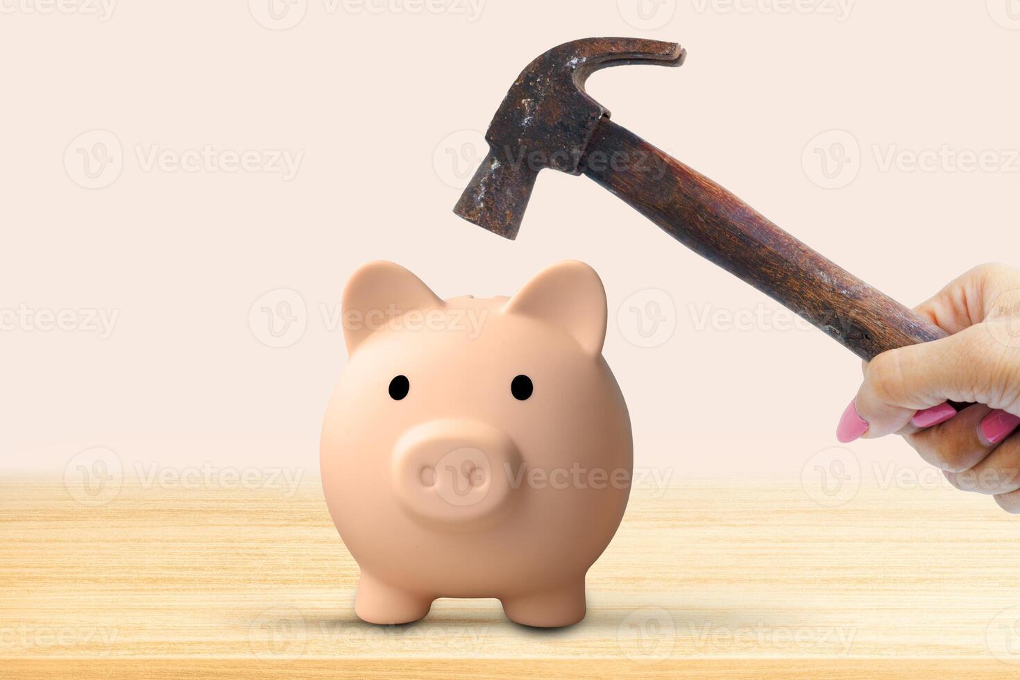 Hand holding a hammer piggy bank isolated on wooden table background. Financial problem photo