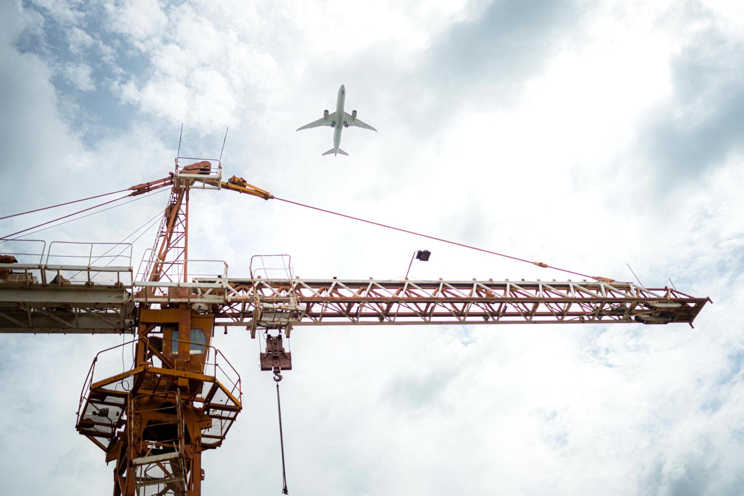Tower crane in at construction site with air plane on sky in the background photo