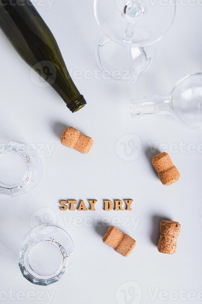 Dry January concept, empty glasses, bottles and corks on a gray background top and vertical view photo
