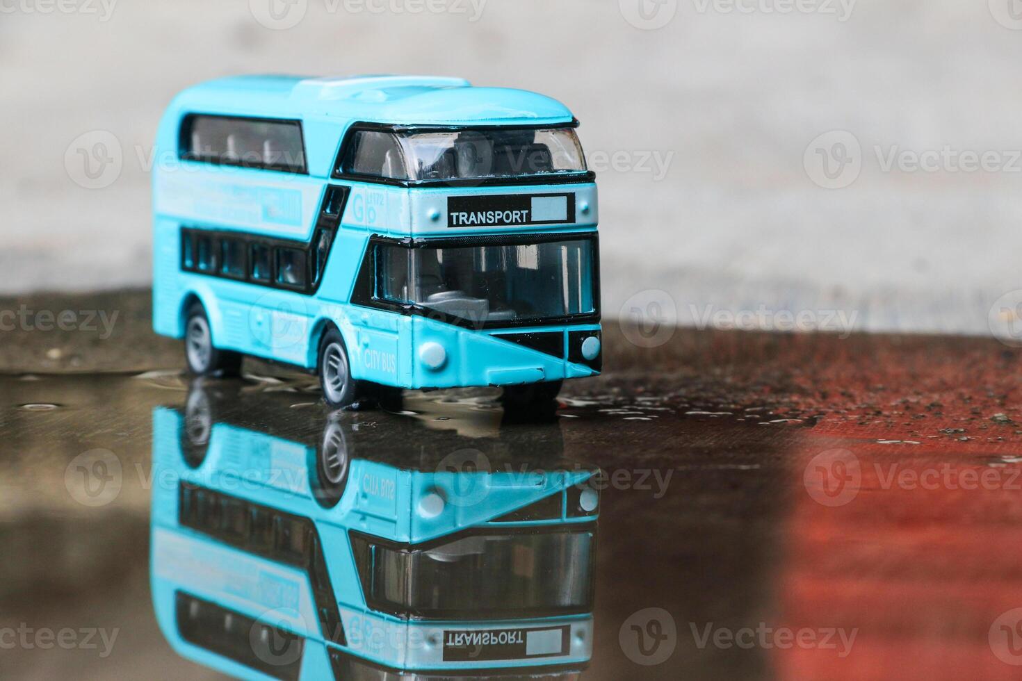 Close up photo of a blue children's toy double-decker bus on an abstract background