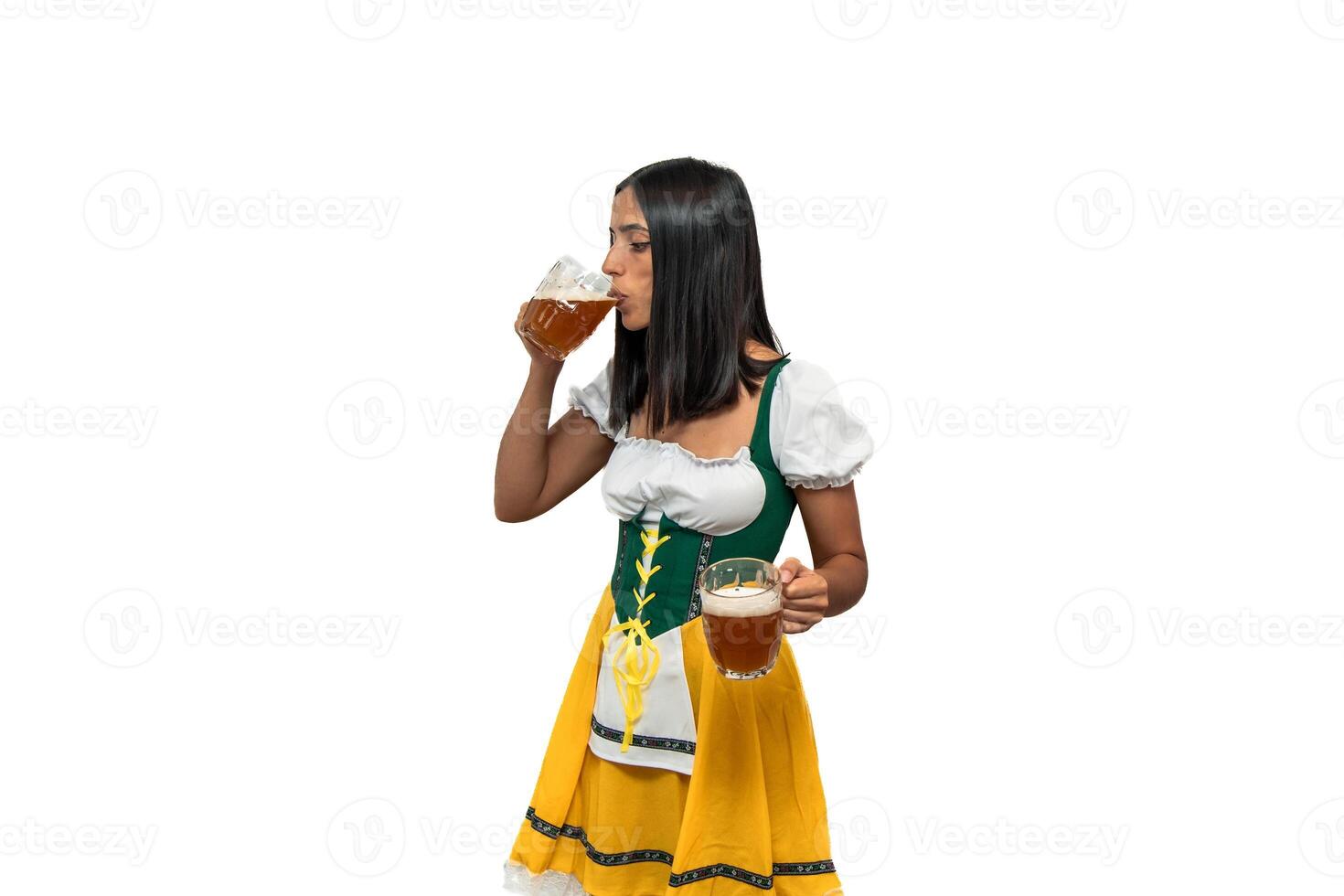 Young bavarian woman drinking a beer glass while holding another in traditional oktoberfest photo