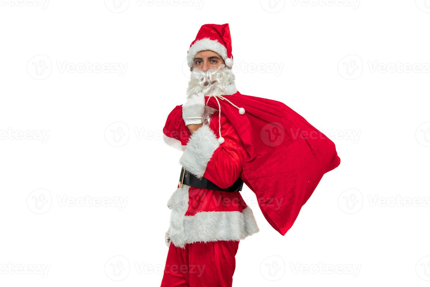 Santa Claus seen from the side holding a sack of gifts while looking at the camera white background photo