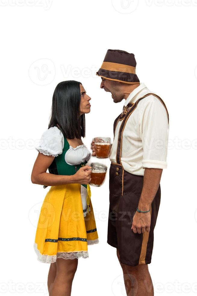 vertical Young bavarian couple arguing and shouting while holding beer glasses at Oktoberfest photo