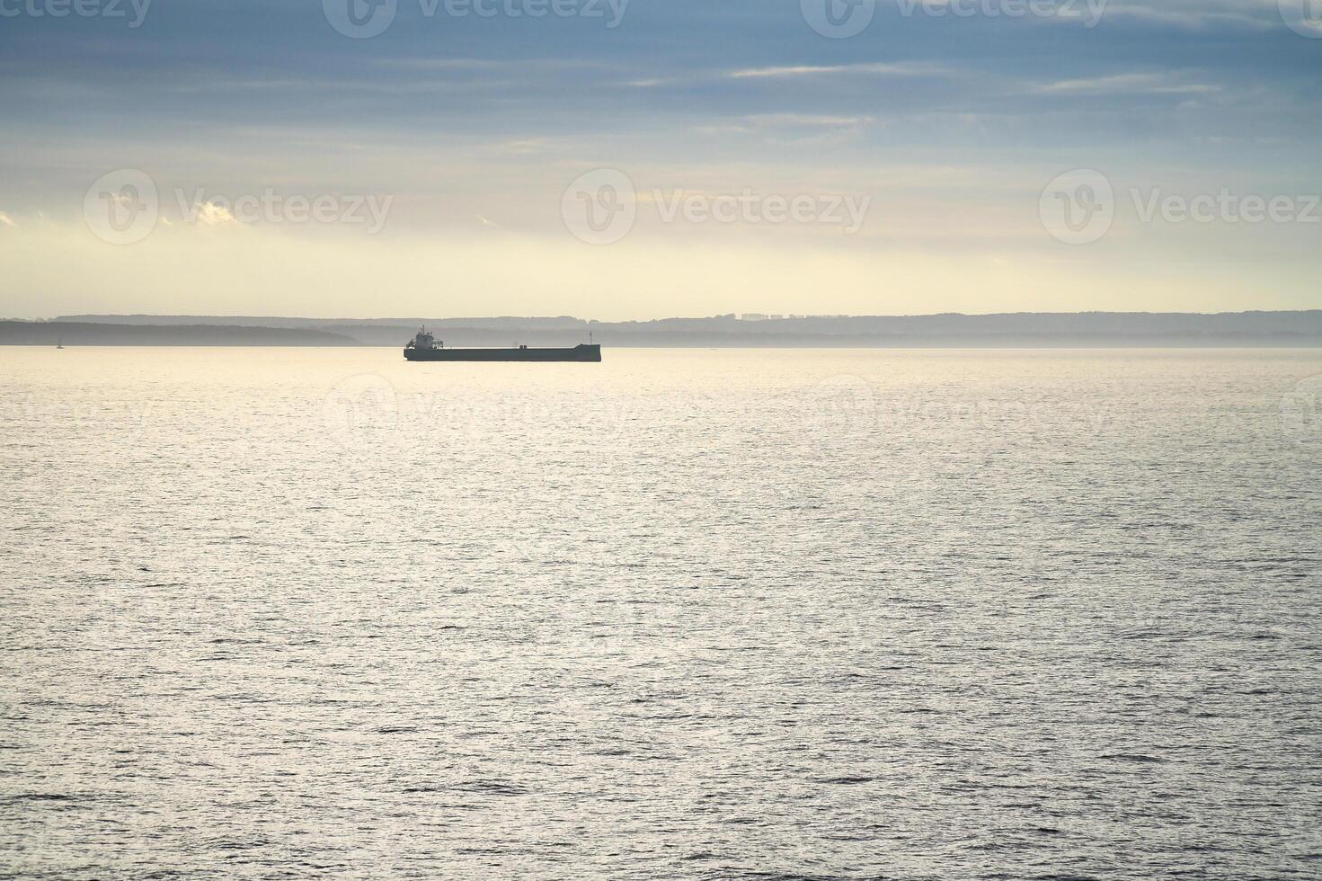 Two cargo ships glide across a calm sea under a clear sky photo