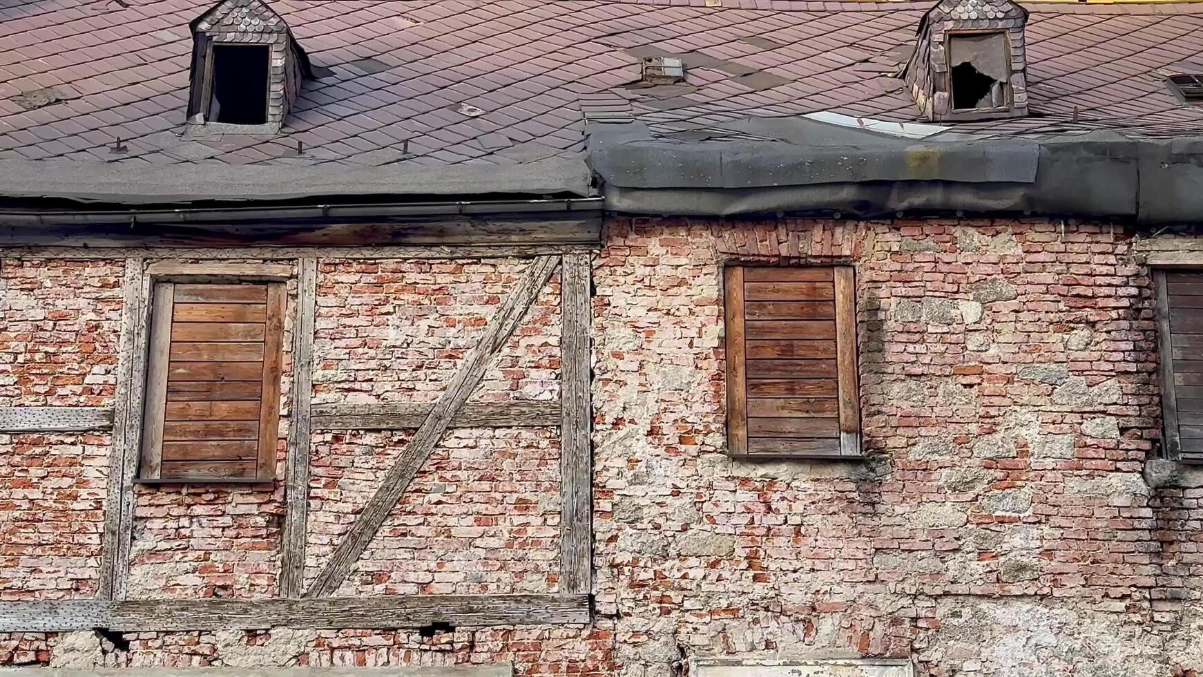 A Weathered Brick Wall displaying Wooden Shutters along with a Distinctive Roof Design photo