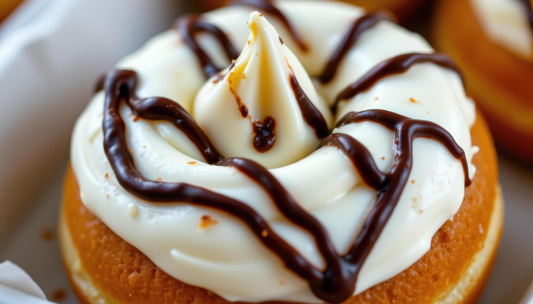 close up view of a cream filled donut with a swirl of whipped topping and chocolate drizzle. photo