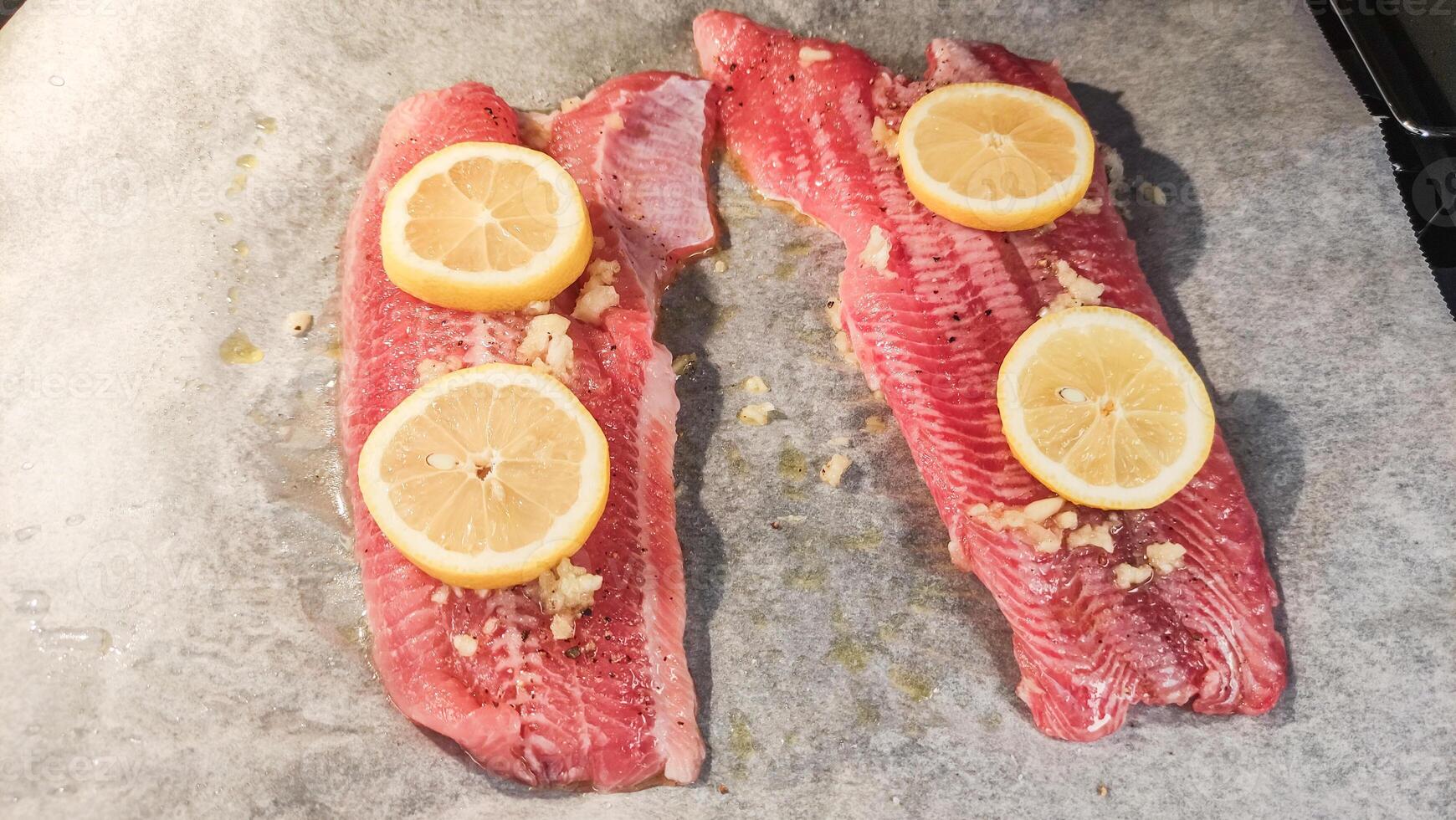 Raw African catfish fillets with lemon and garlic ready for baking photo