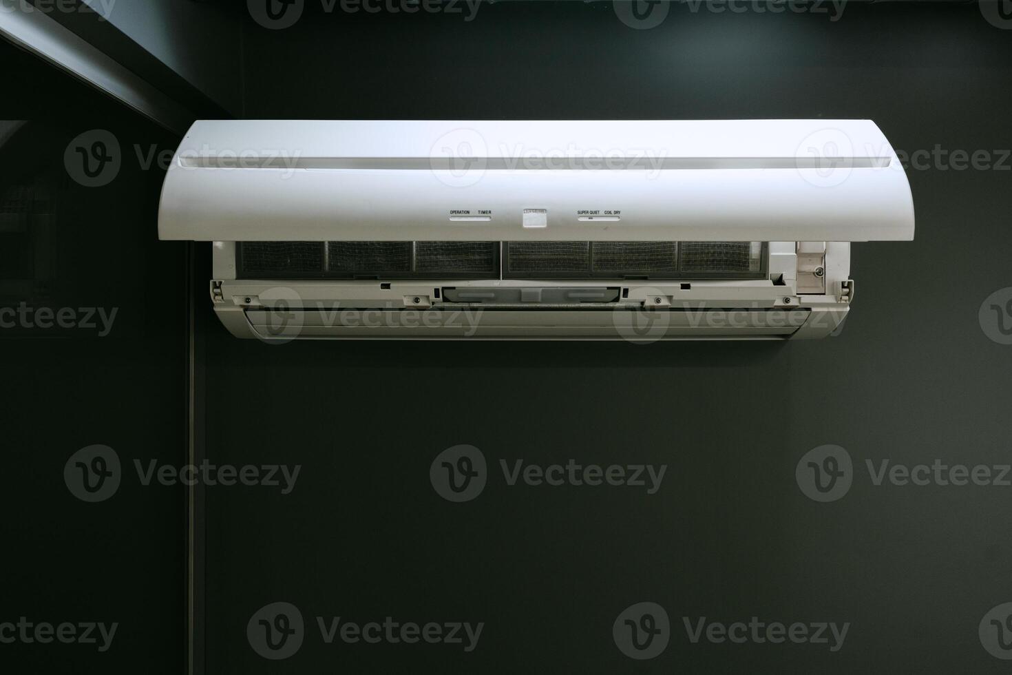 Modern air conditioning unit mounted on a dark wall in a contemporary indoor setting during daytime photo