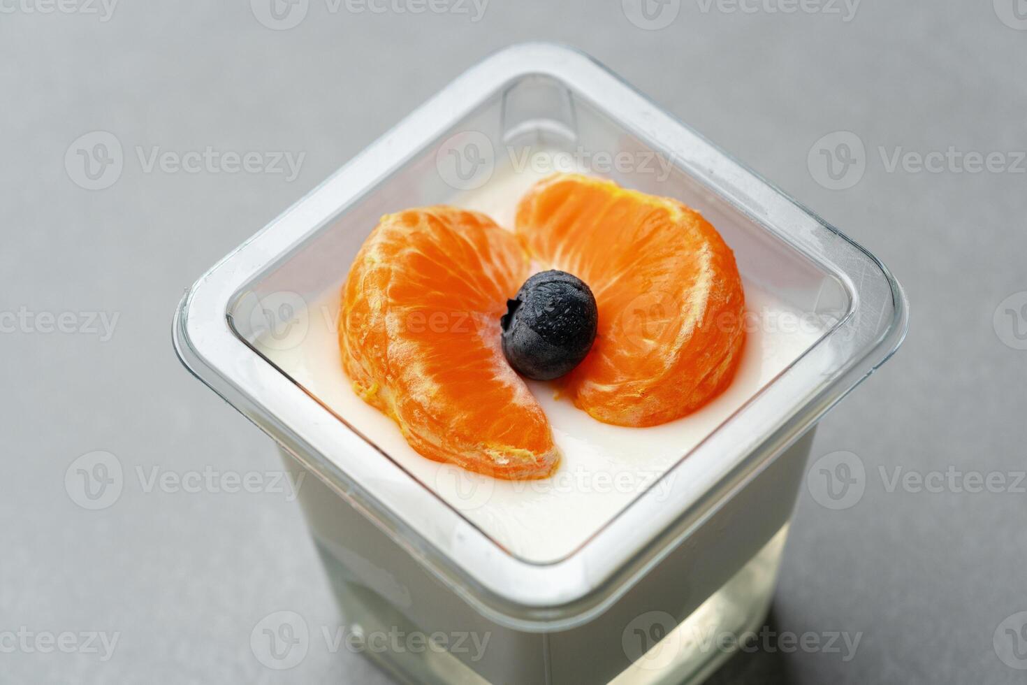 Creamy dessert topped with orange slices and a berry on a gray surface in a modern kitchen setting photo
