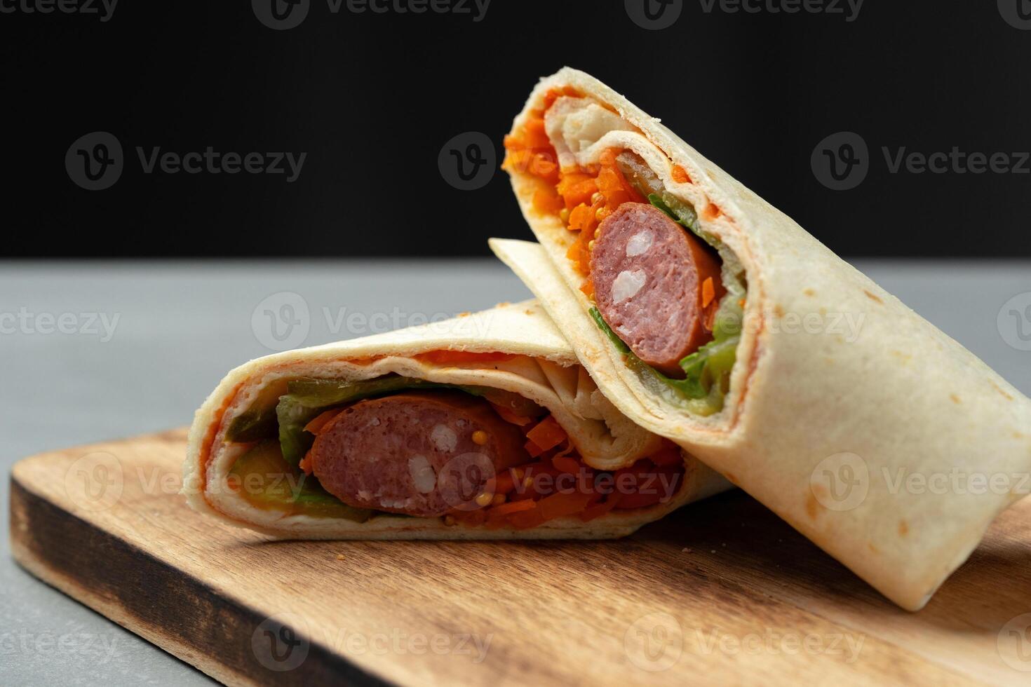 Delicious wraps filled with sausage, vegetables, and spices served on a wooden board photo