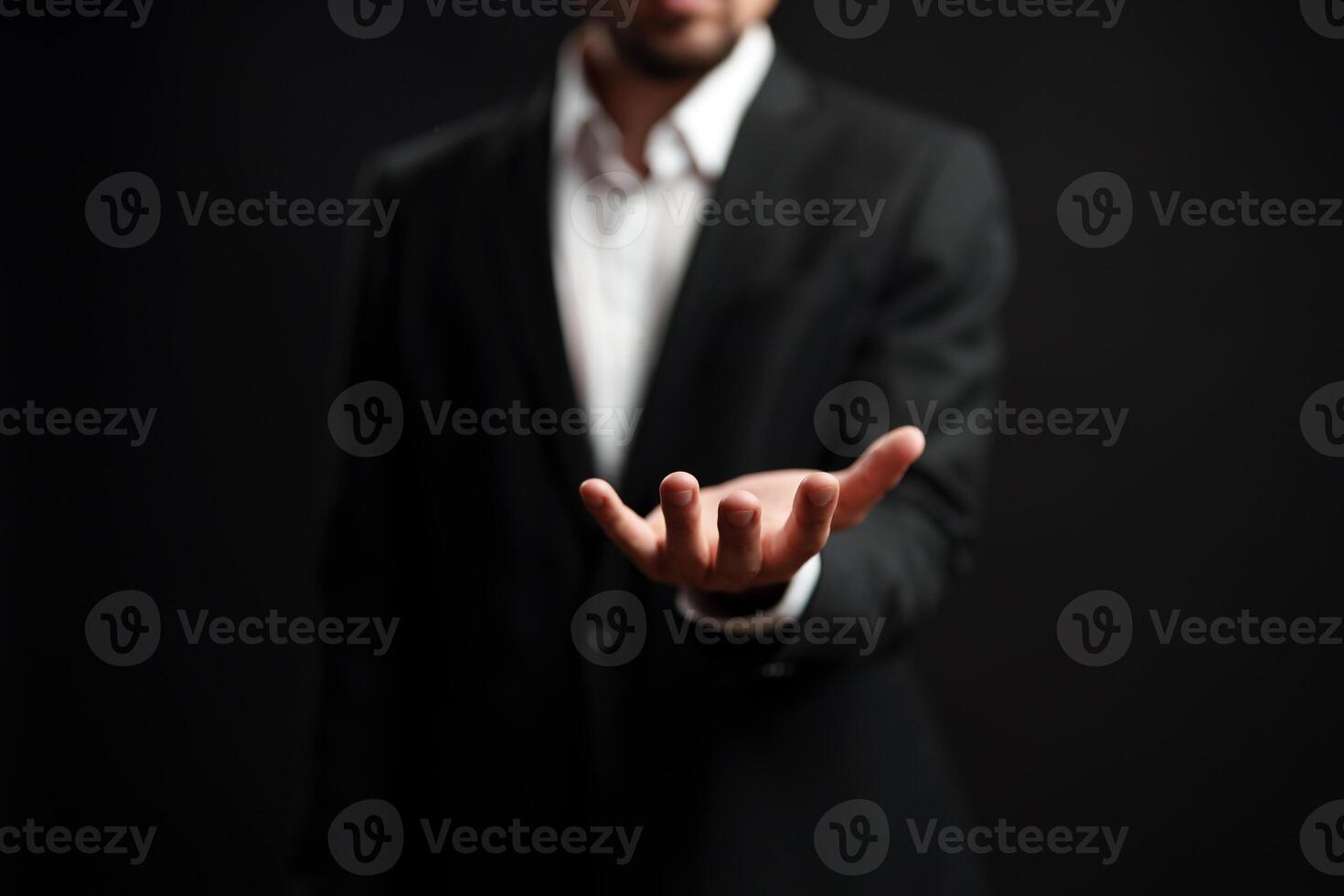 Professional man extending his hand in a welcoming gesture against a dark background photo