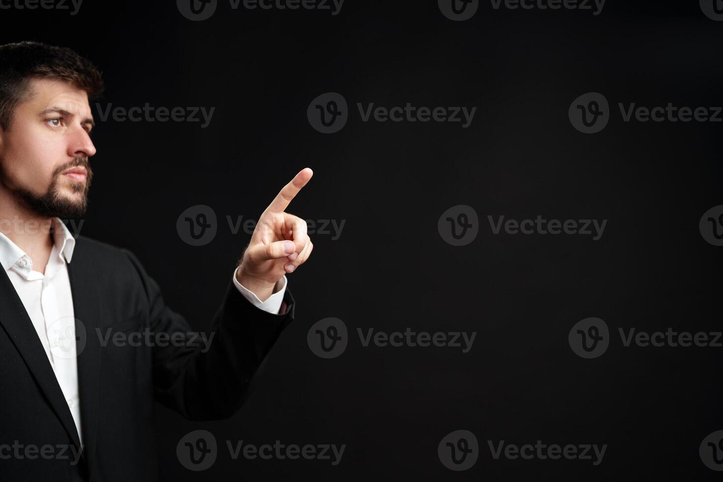 Man in a suit gestures confidently while speaking during a formal presentation in a dimly lit room photo