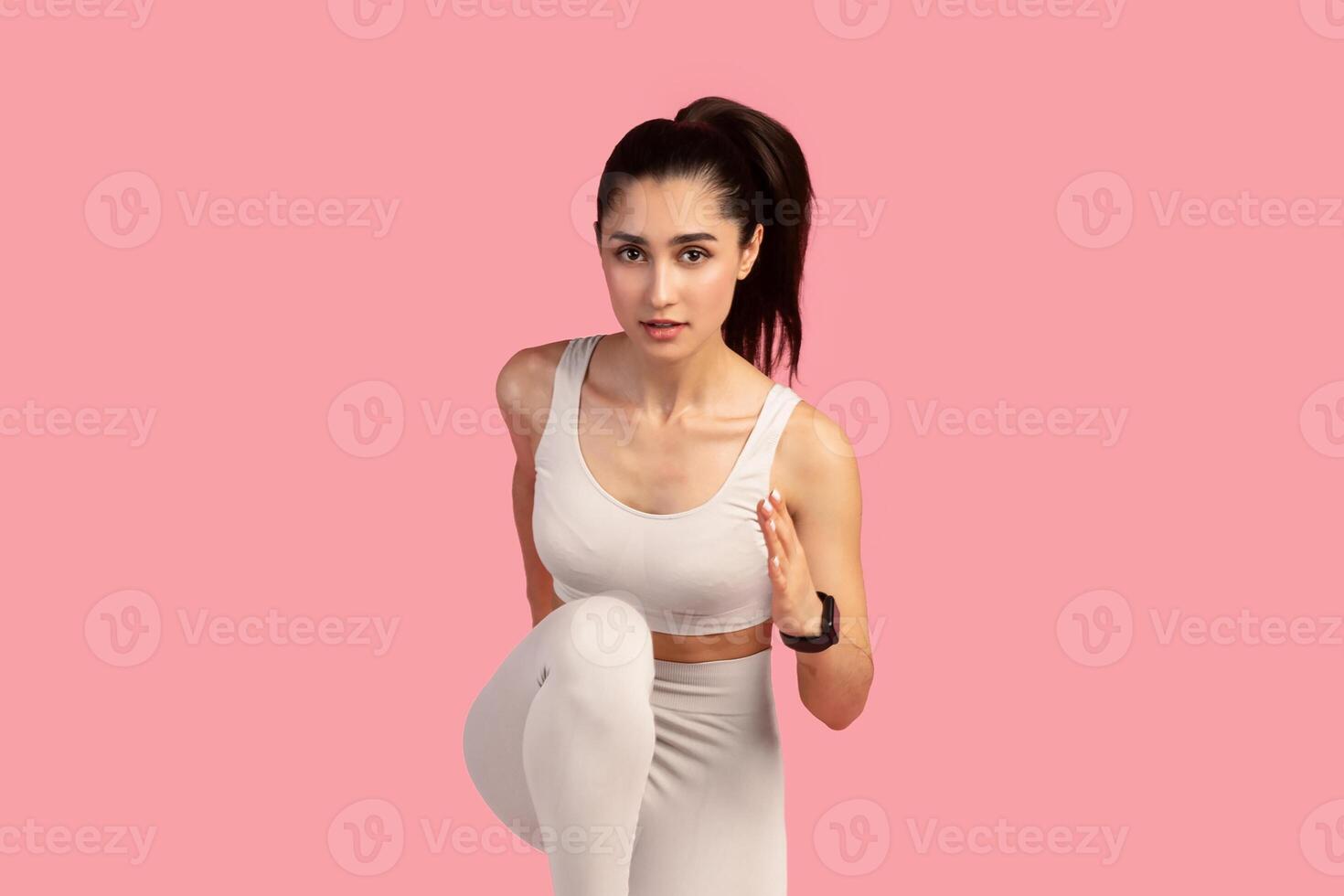 Tabata Routine, Bodyweight Workout. Full body length front shot of determined sporty young lady running towards camera, isolated over pink studio background. Fitness model jogging and sprinting photo