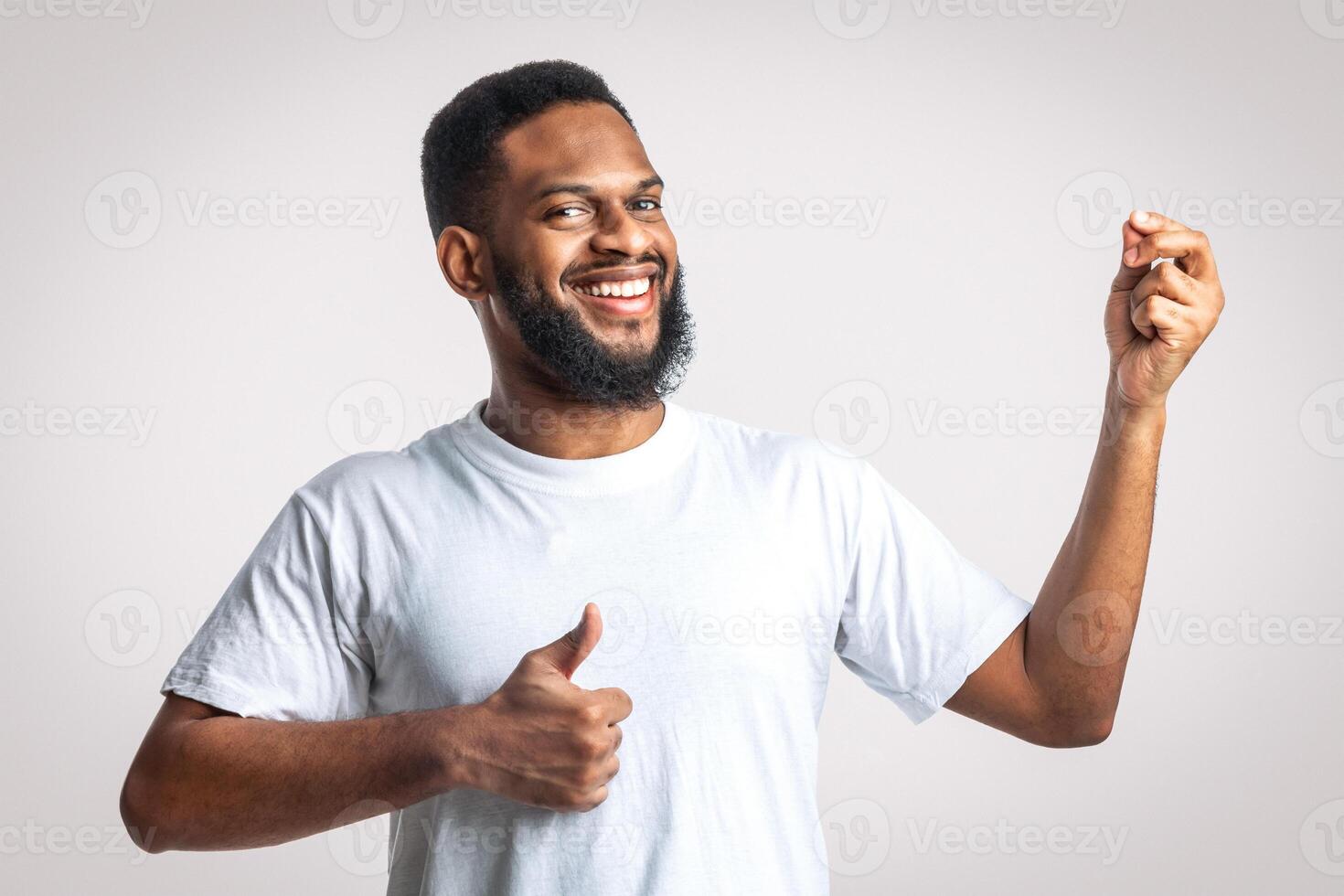 Great Taste. Cheerful Black Man Gesturing Thumbs Up Approving Taste Standing Posing Over White Studio Background, Smiling To Camera. Yummy, I Like This Meal Concept. photo