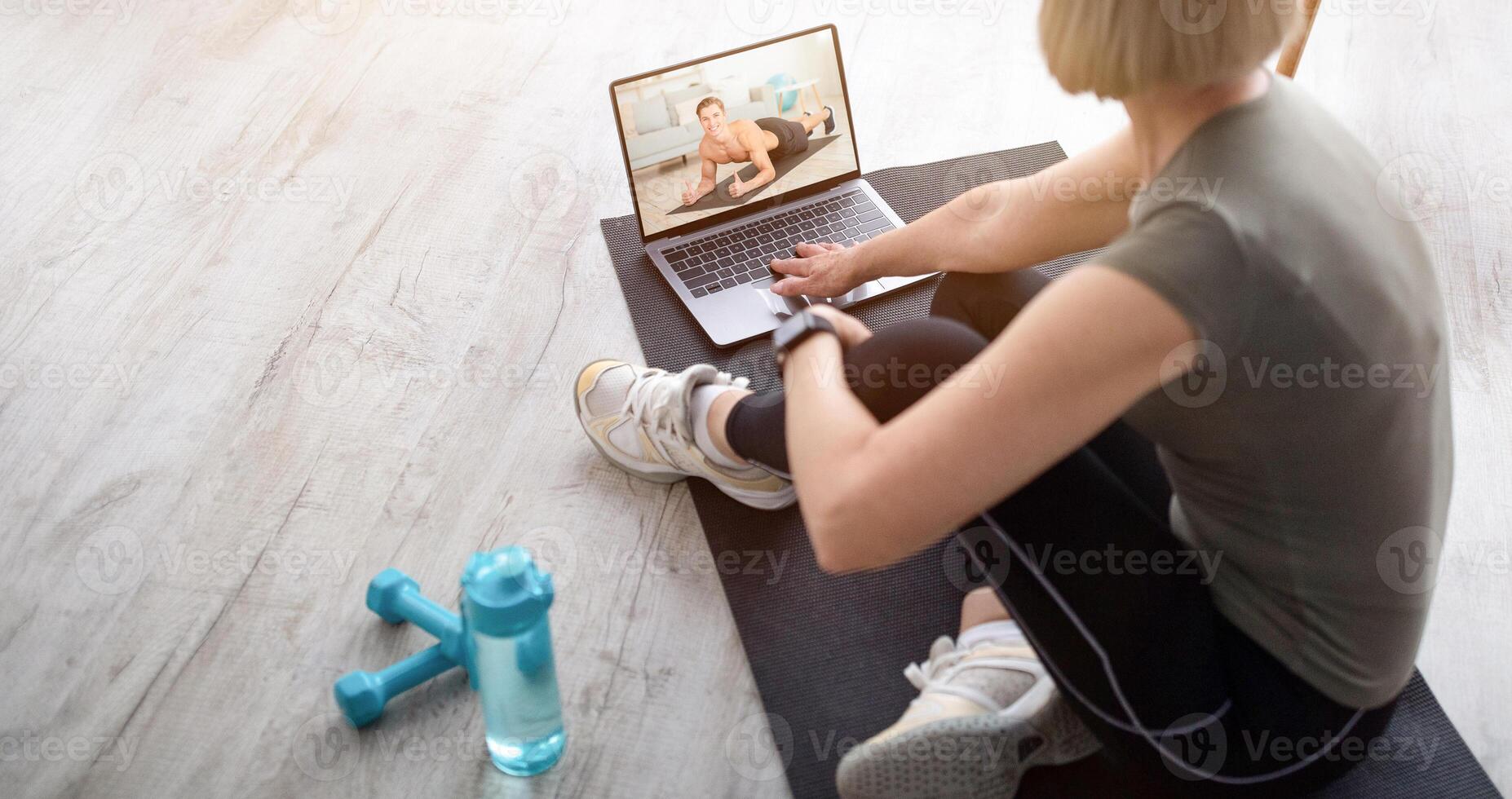Senior woman watching online sports tutorial on laptop, taking break from her domestic training. Mature lady communicating to her personal trainer on web at home, copy space photo
