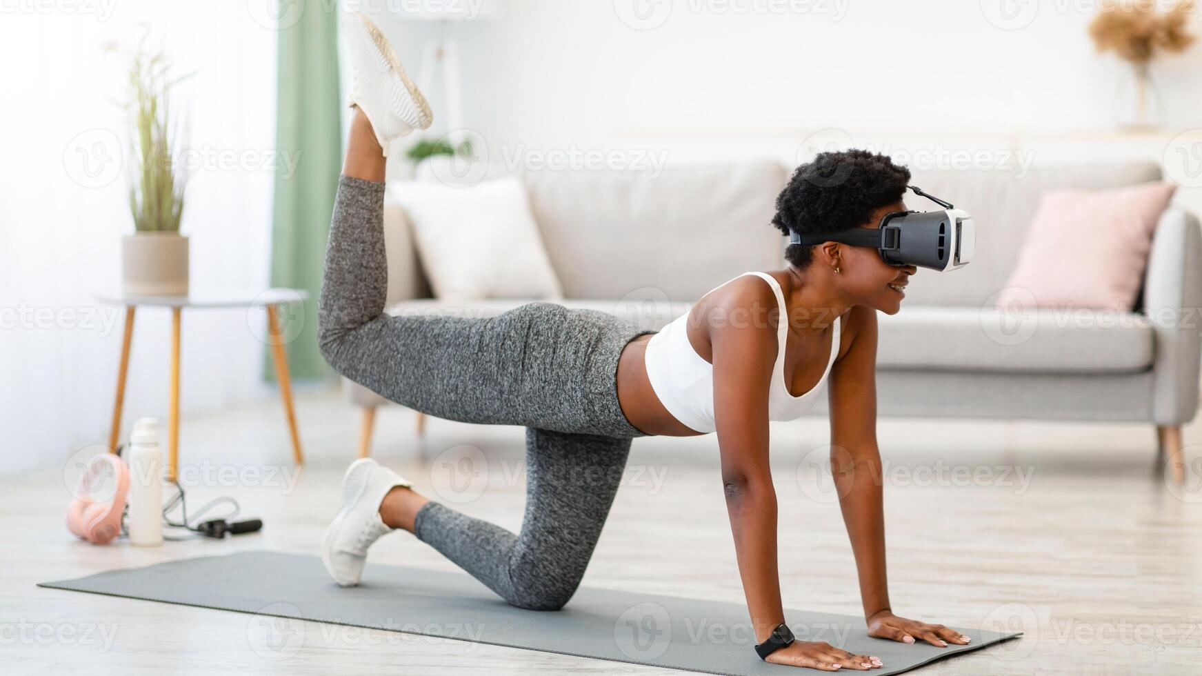 Black Sporty Woman Wearing VR Headset Exercising During Virtual Workout In Digital Gym Training At Home. Augmented Reality Application, Smart Fitness And Futuristic Sport Technologies Concept photo