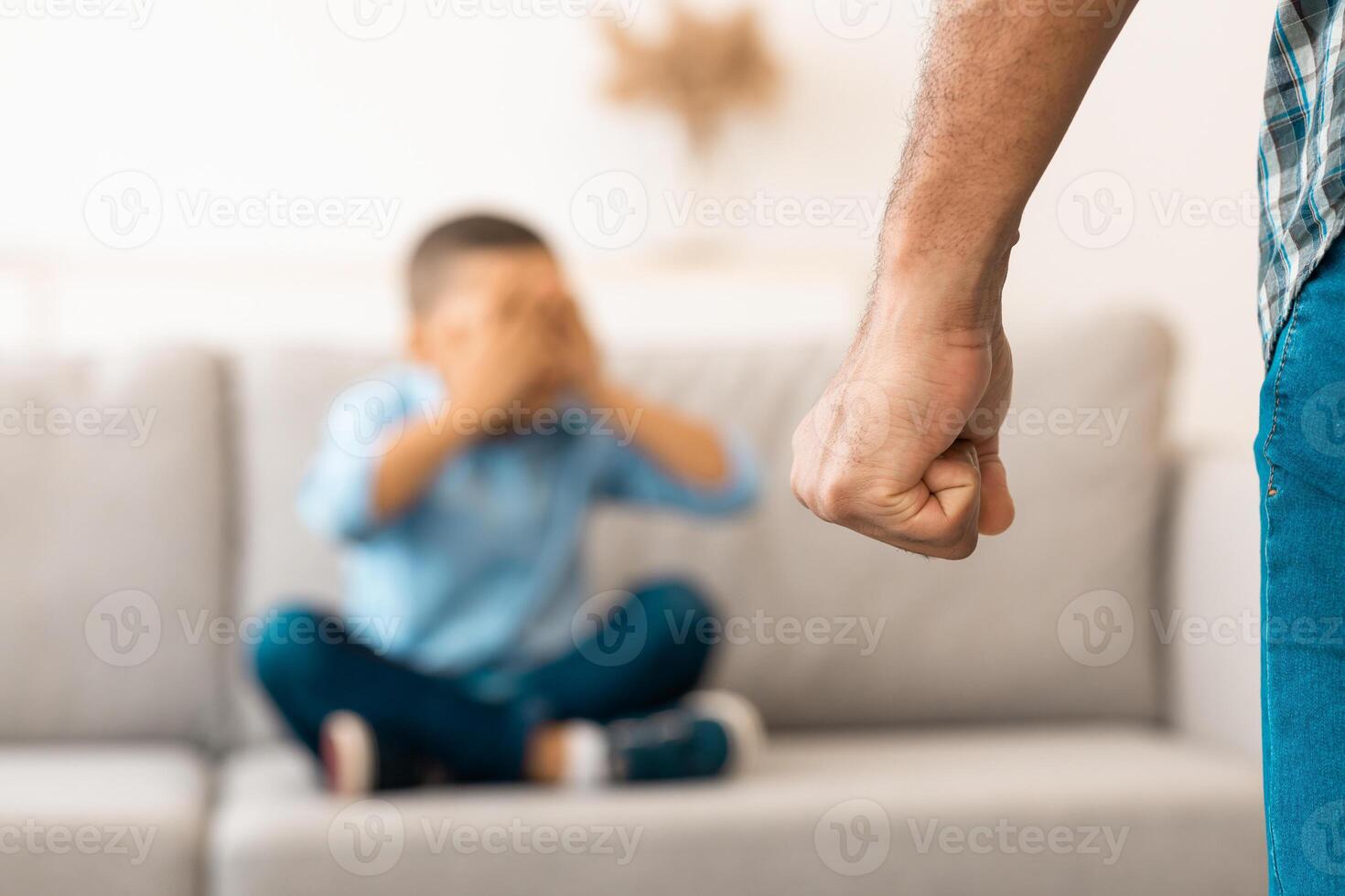 Child Abuse. Unrecognizable Black Father Clenching Fist Ready To Hit Scared Little Son Treatening Boy In Living Room At Home. Domestic Violence On Kid. Cropped, Selective Focus On Male Arm photo