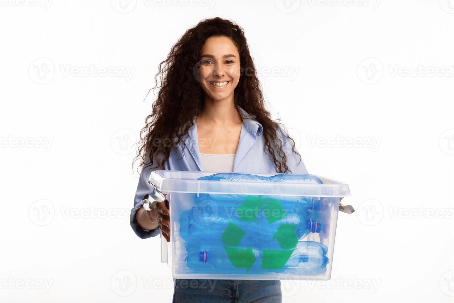 Cheerful Woman Holding Box With Recycle Symbol And Used Plastic Bottles Litter Posing Standing Over White Background In Studio. Waste Recycling And Sorting, Junk Disposal Concept photo
