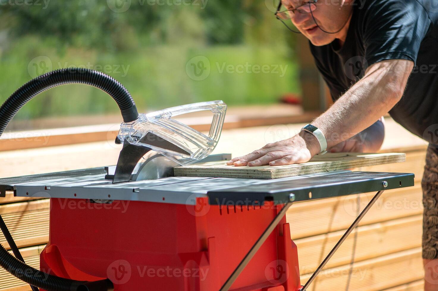 A male carpenter saws chipboard and a wooden board with a circular saw on the machine. Furniture production. photo
