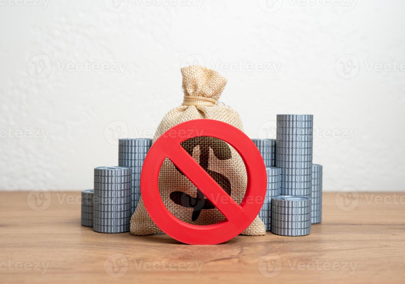 The NO prohibition sign covers the dollar money bag and stacks of coins. Freezing or confiscation of financial assets. Anti-money laundering actions, asset seizure, or economic retaliation. photo
