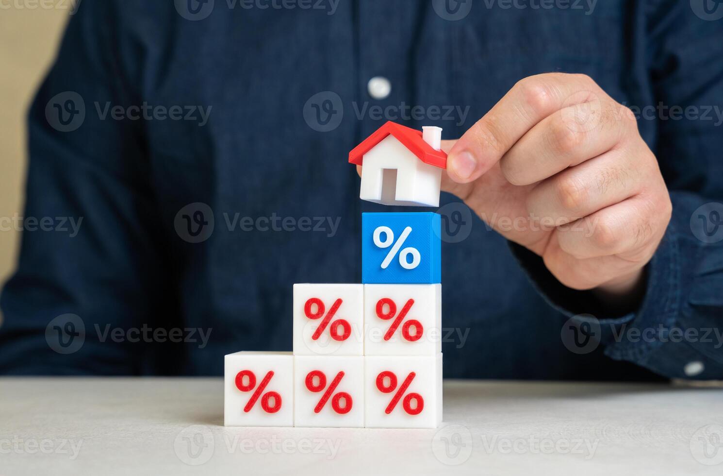 Man puts house on interest rate blocks. Mortgage flexibility, banking relief programs, loan restructuring. Credit holidays can ease financial strain during crises or inflationary periods. photo