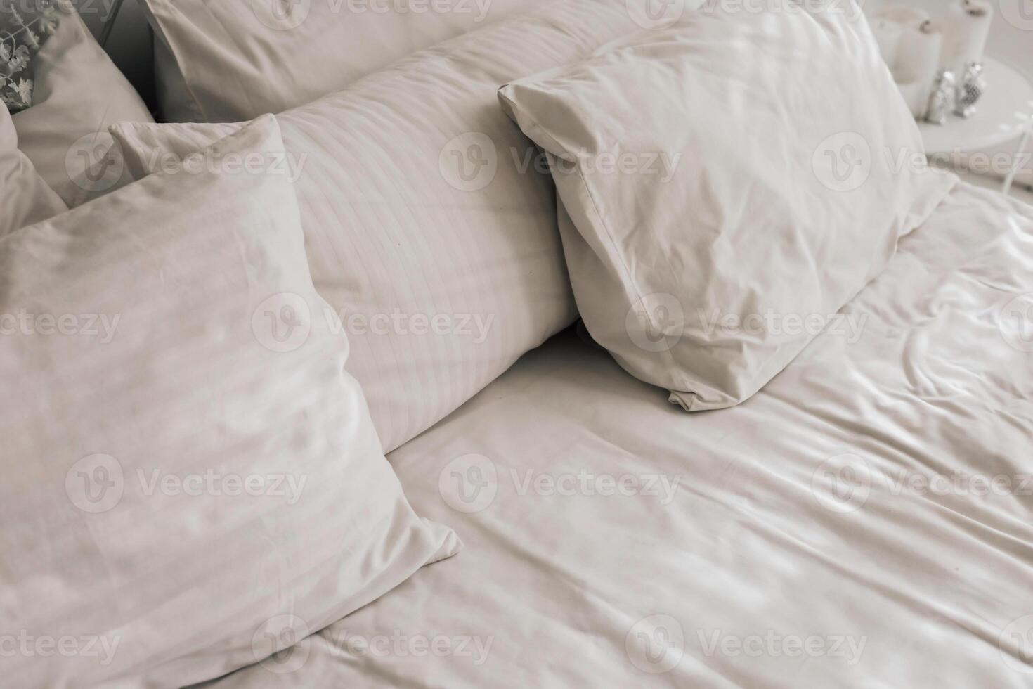 Soft white bedding with plush pillows arranged neatly on a cozy bed in a warm room photo