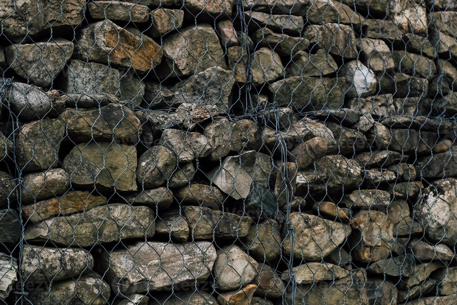 Rock wall constructed with wire mesh for structural support in a natural setting photo