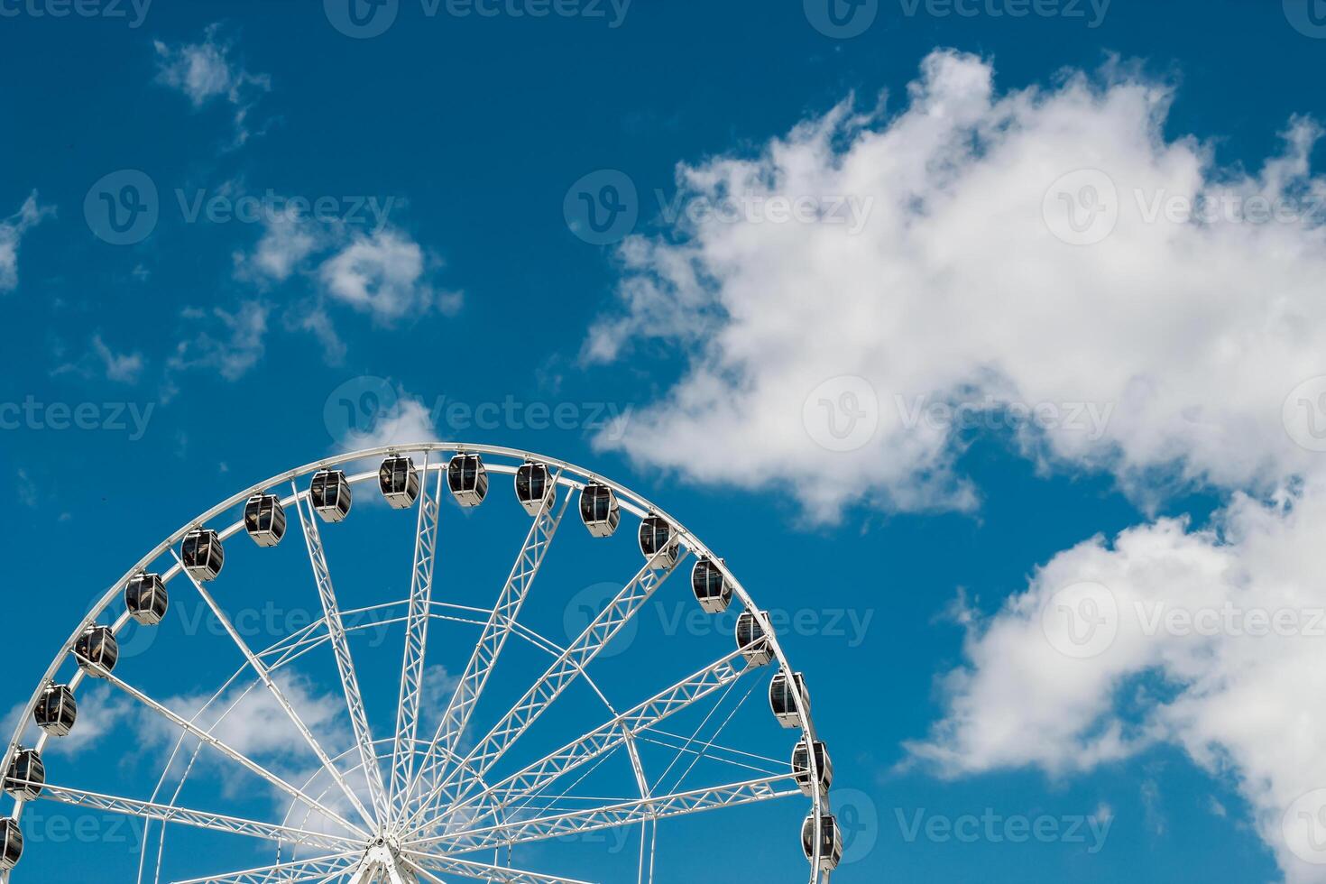 Ferris wheel against a clear blue sky with fluffy white clouds in the afternoon photo